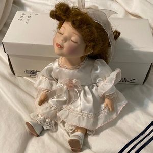 Porcelain doll with white dress and blush pink rosette